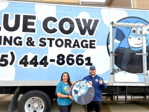 Blue Cow Moving team with a smiling customer in Ankeny, Iowa, standing in front of branded moving truck with logo and phone number visible